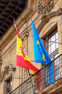 Oviedo, İspanya - 21 Temmuz 2022: Tarihi şehir merkezinin antik binası üzerinde İspanya ve Asturias bayrakları