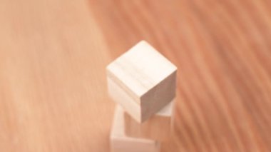 A hand placing a green toy cube on top of a tower of wooden blocks. Environmentally eco friendly and sustainable lifestyle concept