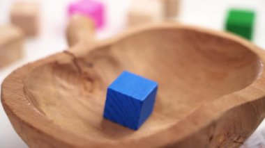 Multi-colored toy cubes falling into a wooden bowl in slow motion. Bright game color blocks. Children development, education and creativity concept