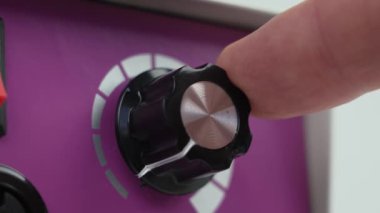 Turning the power knob on the pink panel of the electrical appliance. Household analog station with a dial. Close up. Increase in productivity concept