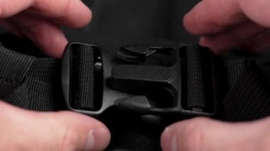Locking black plastic clasp on nylon backpack straps close-up