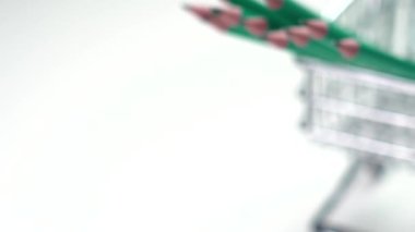 A group of graphite pencils in a mini shopping cart on a white background. Consumerism and back to school idea. Office supply miniature