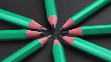Sharpened wooden graphite pencils on a black background arranged in a circle shape. School supplies art creative concept. Rotation