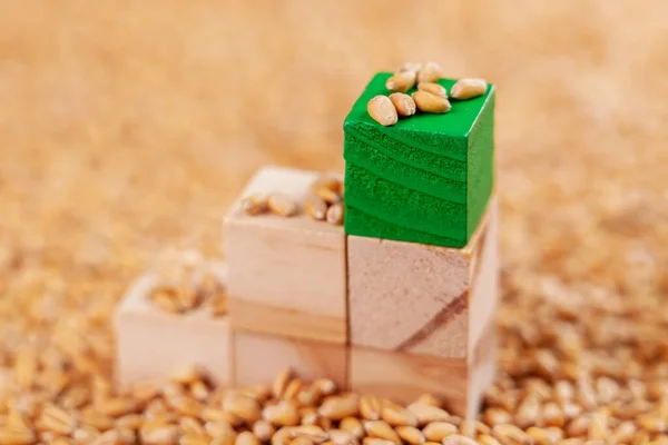 Food business concept. A tower of wooden toy blocks with a green block on top in a pile of wheat seeds