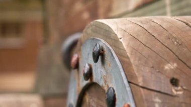 Rusty forged riveted fasteners of an old ancient cracked wooden wheel with iron rim of an antique medieval cannon close-up