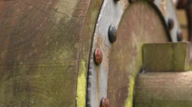 Rusty forged riveted fasteners of an old ancient cracked wooden wheel of an antique medieval cannon close-up