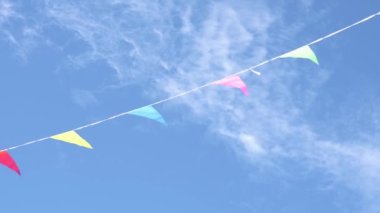 Mavi arka planda çok renkli festival bayrakları. Doğum günü ve karnaval için üçgen renkli bir bayram süsü. Pozitif ve neşe kavramı