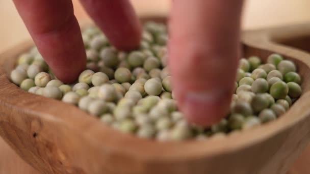 手はスローモーションで完全な素朴な木製のボウルから全体の乾燥した緑のエンドウ豆の一握りを取ります 接近中だ 生の乾燥したマメ科植物 ピスムサティウム ファブリーア — ストック動画