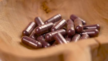 Kırsal ahşap bir kasede dut özü bulunan sağlık kapsülleri. Kurutulmuş yabanmersini tozlu haplar. Alternatif tıp ve besin takviyeleri konsepti. Görme desteği gıda takviyesi. Döndürme