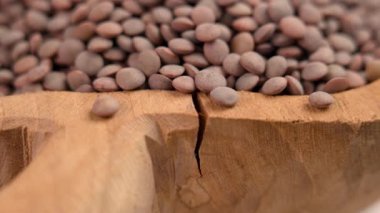 Kırsal ahşap bir tabakta oyulmuş kahverengi kuru mercimek. Dönen Hintli pişmemiş fasulye