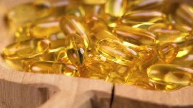 Çatlak ahşap bir kasede sarı Omega 3 kapsülleri. SağIık desteği. Kırsal bakış açısı. Döndürme