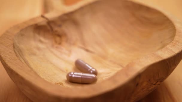 ビタミンサプリメントカプセル木製の素朴な容器に木製の茶色の背景にゆっくりと動きに落ちる 食事用の錠剤が閉じます 代替医療の概念 — ストック動画
