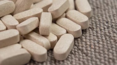 C vitamini hapları yakın çekim. Kaba bir jüt kumaşa bej ilaç yığını. Makro atış. Döndürme. Sağlık kavramı