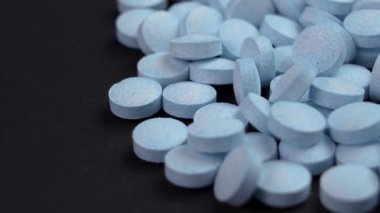 Siyah arka planda mavi yuvarlak baş ağrısı kesici hapları. Makro atış. Döndürme