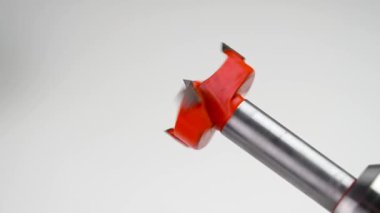Forstner 'ın beyaz arka planda elektrikli matkapla dönen kırmızı metal kesicisi var. Aracın işleyişinin gösterimi. Yakın plan. Yavaş çekim
