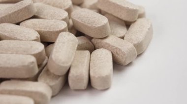 Beyaz arka planda bej ilaç baş ağrısı hapları. Makro atış. Döndürme