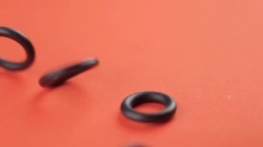 Renkli turuncu arka plana yakın çekimde lastik contalar düşüyor. Hidrolik yedek parçalar. Döndürme
