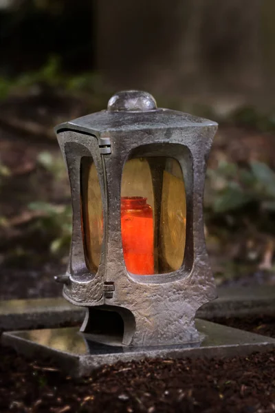 funeral lantern in a cemetery at dusk with a burning candle