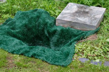 Mezara gömülmeden önce yeşil bir hasırla kaplı küçük açık bir mezar.