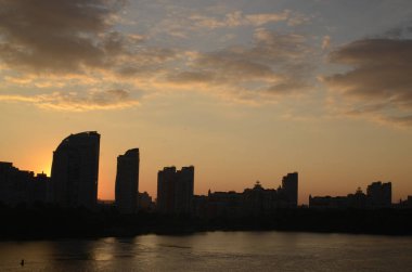Binaların manzarası ve nehrin üzerindeki gün batımı gökyüzü