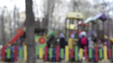 unfocused footage of children playing at playground and people walking on foreground