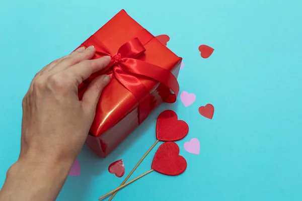 Caja roja con cinta roja sobre un fondo de papel azul. Regalo de San Valentín con confeti y decoración — Foto de Stock