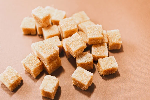 Brown sugar cubes close up on brown paper background — ストック写真