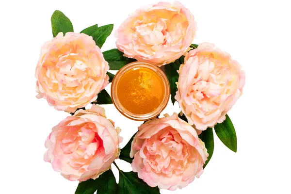 Liquid sugar paste for hair removal in a bowl with peony flower on white background. The concept of body care, beauty treatments.