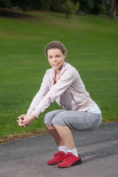 Young sporty woman makes knee bends — Stock Photo, Image