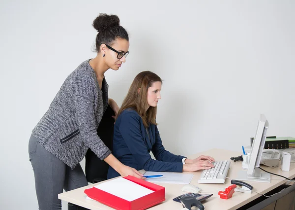 Dos mujeres frente a la computadora en la oficina Imagen de stock