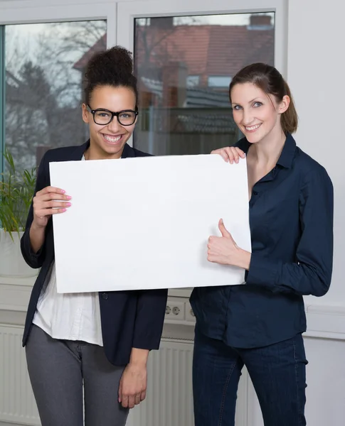 Dos mujeres están mostrando una pizarra blanca — Foto de Stock