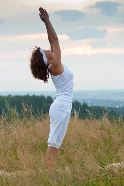 Femme faisant du yoga pendant le lever du soleil — Photo