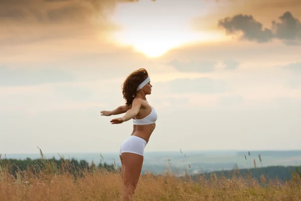 Femme faisant du yoga pendant le lever du soleil — Photo