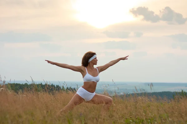 Femme faisant du yoga pendant le lever du soleil — Photo