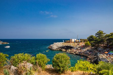 17 Ağustos 2021 - Otranto, Puglia, İtalya - Porto Badisco 'nun küçük plajı, ünlü sahil beldesi Salento. Turistler yaz tatillerini geçirirler. İnsanlar eğleniyor ve denizde yüzüyor..