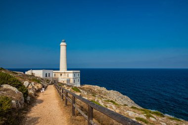 Punta Palascia 'nın deniz feneri, Otranto, Lecce, Salento, Puglia, İtalya. Pelerin İtalya 'nın en doğu noktasıdır. Küçük bir kız deniz fenerine giden yolda yürüyor. Yazın mavi gökyüzü.