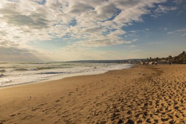 Santa Marinella, Roma, Lazio, İtalya - Bir kış günü Roma kıyıları Santa Severa. Birçok insan gün batımında sahilde gezer ve güneşin tadını çıkarır. Dalgalı deniz, rüzgâr, bulutlu mavi gökyüzü