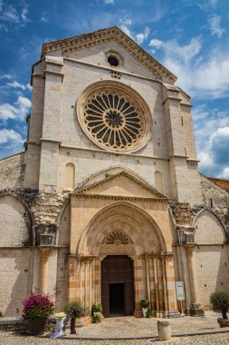 Priverno, Latina, Lazio, Italy - The facade of the church of the Fossanova abbey. The large rose window and the portal with the pointed arch. The columns and the tympanum. Cloudy blue sky.