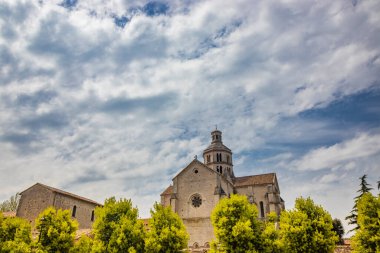 Priverno, Latina, Lazio, İtalya - Fossanova Manastırı. Kilise ve küçük ortaçağ köyünün binaları dışarıdan görülüyor. Haçlı yüksek çan kulesi. Bulutlu mavi gökyüzü.