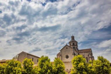 Priverno, Latina, Lazio, İtalya - Fossanova Manastırı. Kilise ve küçük ortaçağ köyünün binaları dışarıdan görülüyor. Haçlı yüksek çan kulesi. Bulutlu mavi gökyüzü.