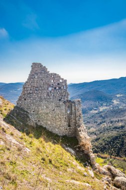 Lazio 'daki küçük Tolfa köyü. Uçurumun tepesinde duran kalenin antik duvarlarının bir parçası. Yıkılmış taş bloklardan ve tuğlalardan oluşan duvarın yıkıntıları..