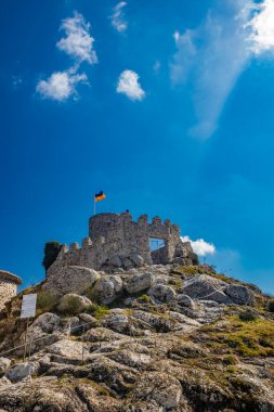 Lazio 'daki küçük Tolfa köyü. Kalenin antik duvarlarının kalıntıları uçurumun tepesinde. Kalenin kalıntıları. Ukrayna bayrağının çekildiği kule dayanışma işareti olarak kullanılıyor..