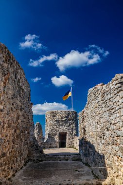 Lazio 'daki küçük Tolfa köyü. Kalenin antik duvarlarının kalıntıları uçurumun tepesinde. Kalenin kalıntıları. Ukrayna bayrağının çekildiği kule dayanışma işareti olarak kullanılıyor..