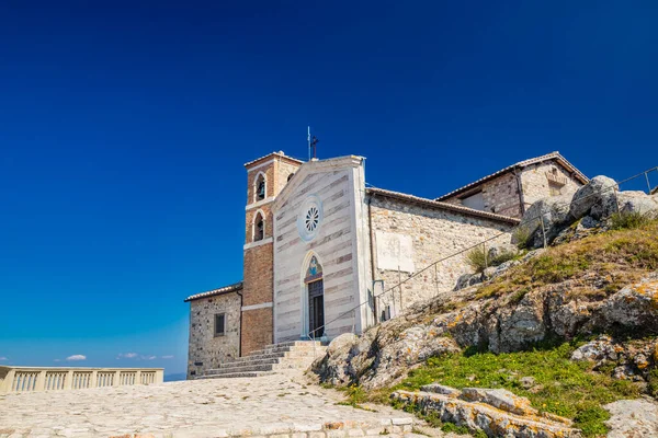Lazio 'daki küçük Tolfa köyü. Madonna della Rocca 'nın sığınağı uçurumun tepesinde, kalenin bulunduğu yerde. Gül pencereli ön cephe ve çan kulesi.