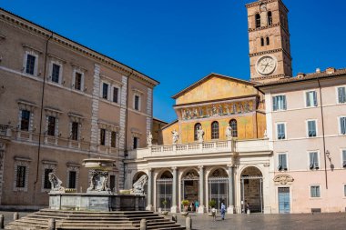 Trastevere 'deki Santa Maria Bazilikası, Roma' nın merkezinde bir meydanda. Portico ve mozaikli cephe, saatli çan kulesi ve yazıtlı çeşme..