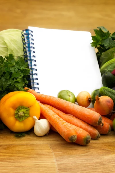 Diferentes verduras frescas con libro de cocina vacío — Foto de Stock