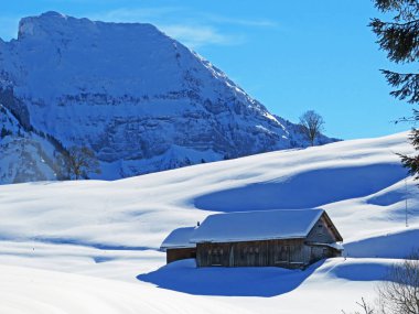 İsviçre dağ kulübeleri kışlık giysiler içinde ve Alpstein dağ sırasının yamaçlarında taze bir kar örtüsüyle Schwaegalp, İsviçre (Schweiz)