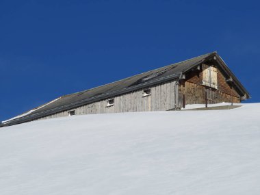 İsviçre dağ kulübeleri kışlık giysiler içinde ve Alpstein dağ sırasının yamaçlarında taze bir kar örtüsüyle Schwaegalp, İsviçre (Schweiz)