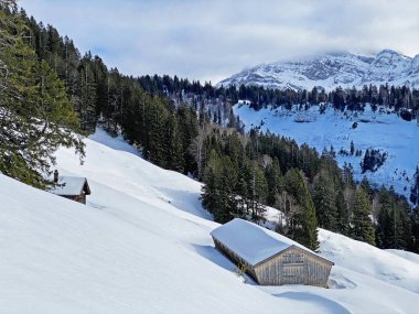 İsviçre dağ kulübeleri kışlık giysiler içinde ve Alpstein dağ sırasının yamaçlarında taze bir kar örtüsüyle Schwaegalp, İsviçre (Schweiz)