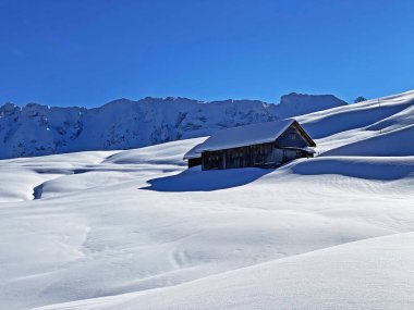 İsviçre dağ kulübeleri kışlık giysiler içinde ve Alpstein dağ sırasının yamaçlarında taze bir kar örtüsüyle Schwaegalp, İsviçre (Schweiz)